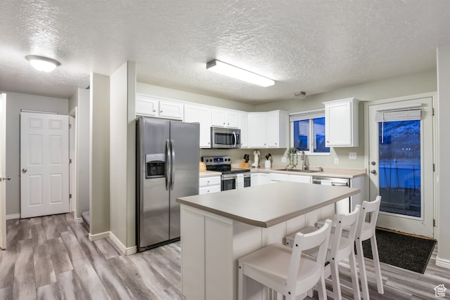 486 N 200 E, Santaquin, UT 84655 - kitchen with stainless steel appliances, light wood-type flooring, a sink, a textured ceiling, and baseboards