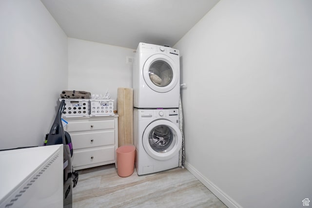 laundry room with stacked washing maching and dryer and light hardwood / wood-style flooring