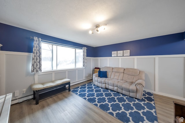 living room featuring hardwood / wood-style floors, a textured ceiling, and a baseboard heating unit