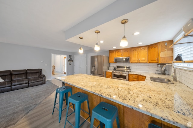 kitchen with dark wood-type flooring, a kitchen breakfast bar, sink, decorative backsplash, and stainless steel appliances