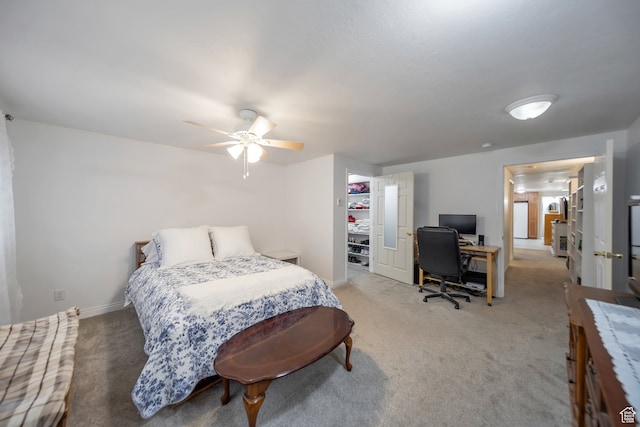 carpeted bedroom with a walk in closet, ceiling fan, and a closet