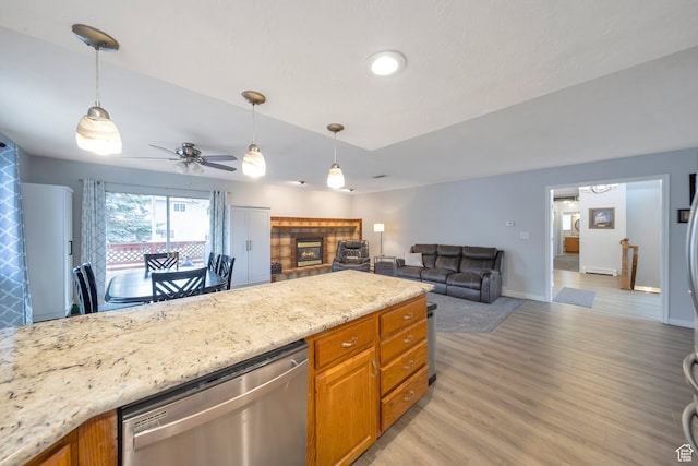 kitchen featuring dishwasher, a tile fireplace, ceiling fan, light stone countertops, and light wood-type flooring