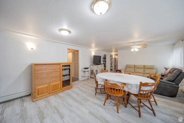 dining area with ceiling fan, a baseboard radiator, and light hardwood / wood-style flooring