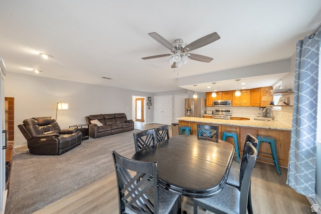 dining area featuring ceiling fan, light hardwood / wood-style floors, and sink
