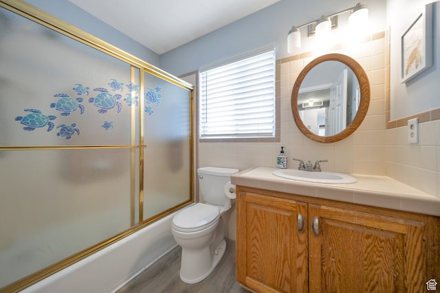 full bathroom featuring vanity, hardwood / wood-style flooring, tile walls, enclosed tub / shower combo, and toilet