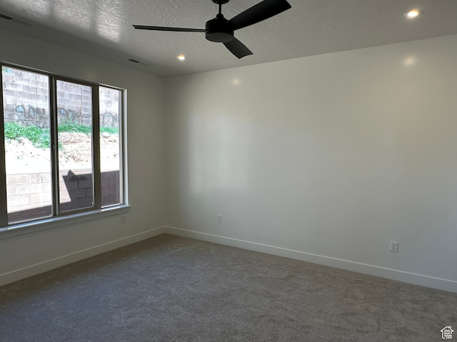 carpeted spare room with ceiling fan and a textured ceiling