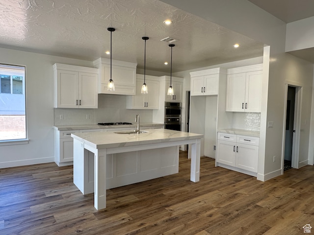 kitchen with a center island with sink, dark hardwood / wood-style floors, white cabinetry, and a textured ceiling