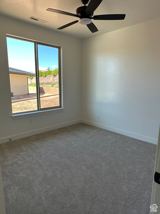 carpeted spare room with ceiling fan and a textured ceiling