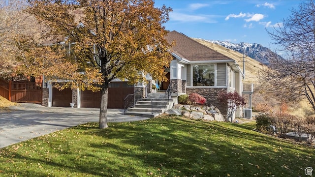 view of front facade featuring a mountain view, cooling unit, a front yard, and a garage