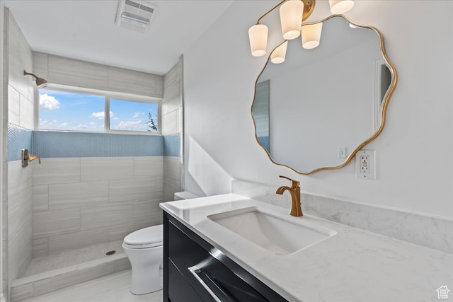 bathroom with vanity, toilet, and a tile shower