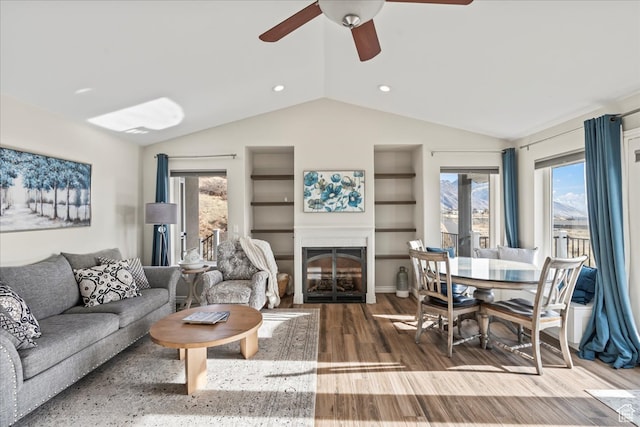 living room with hardwood / wood-style floors, ceiling fan, built in features, and vaulted ceiling