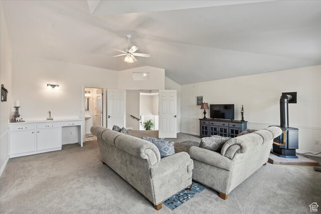 carpeted living room with lofted ceiling, ceiling fan, and a wood stove