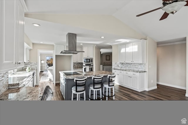 kitchen featuring island exhaust hood, white cabinets, appliances with stainless steel finishes, and a kitchen island