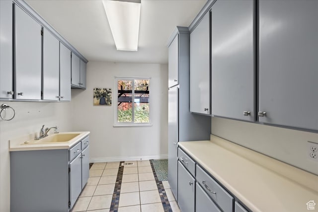 kitchen with gray cabinets, sink, and light tile patterned flooring
