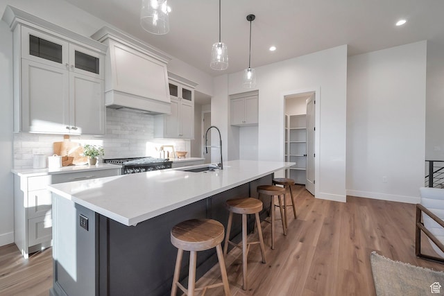 176 S 1150 E, Pleasant Grove, UT 84062 - kitchen with a sink, baseboards, tasteful backsplash, light wood-style flooring, and a kitchen island with sink
