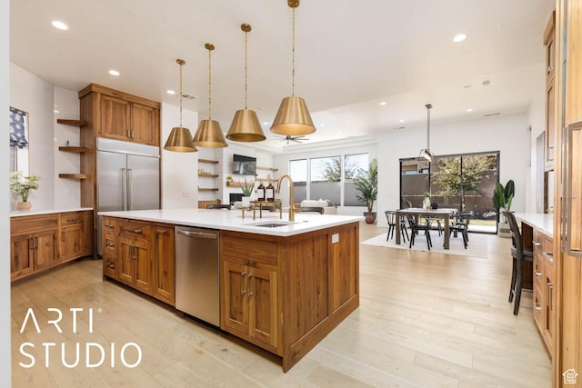 kitchen featuring a center island with sink, brown cabinetry, appliances with stainless steel finishes, light countertops, and pendant lighting