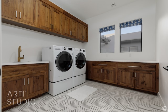 washroom featuring washing machine and clothes dryer, cabinet space, a sink, and visible vents