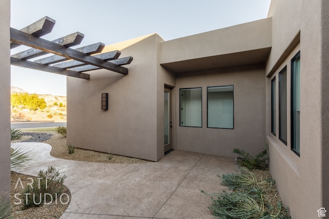 exterior space with a patio area, a pergola, and stucco siding