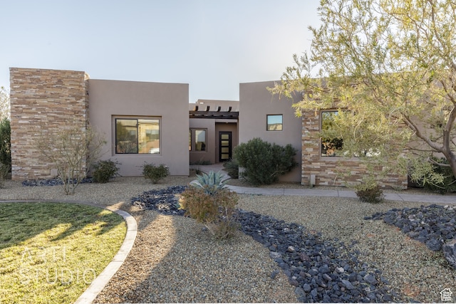 southwest-style home featuring stone siding and stucco siding