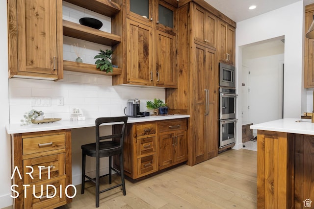 kitchen featuring brown cabinets, stainless steel appliances, light countertops, open shelves, and backsplash