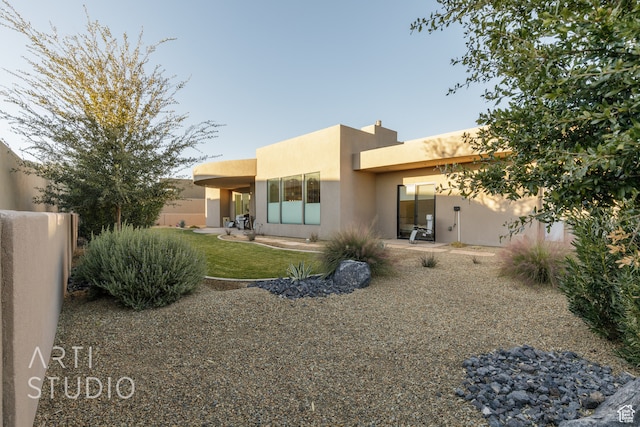 rear view of house with a patio area, fence, and stucco siding