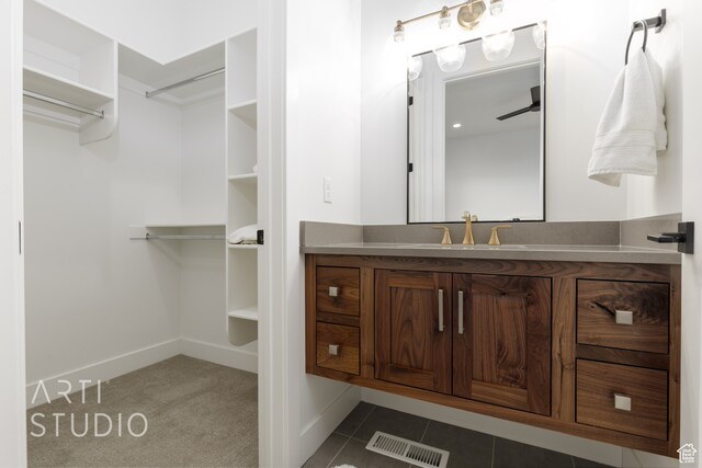 bathroom featuring visible vents, a spacious closet, vanity, baseboards, and tile patterned floors
