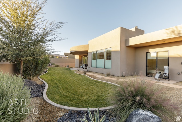rear view of property with a patio, fence, a lawn, and stucco siding