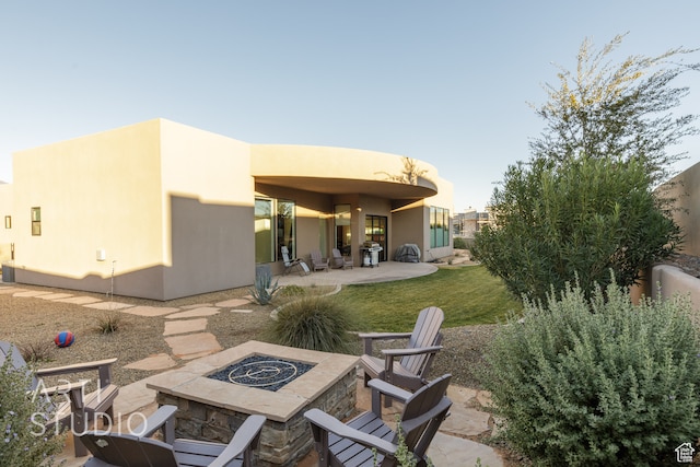 back of house featuring a patio area, a fire pit, and stucco siding