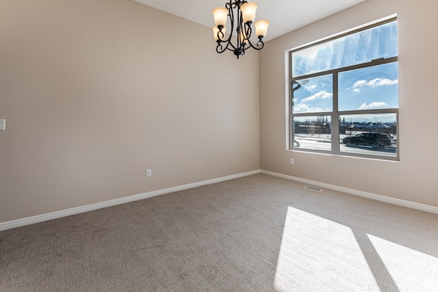 carpeted empty room featuring an inviting chandelier