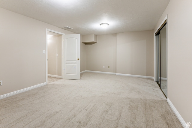 interior space featuring a textured ceiling and light colored carpet