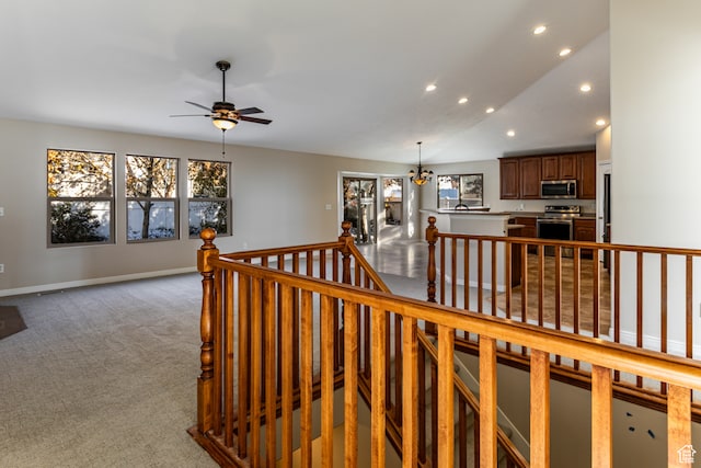 stairs featuring ceiling fan with notable chandelier, carpet floors, and vaulted ceiling