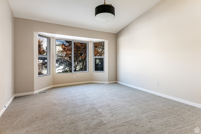 carpeted spare room featuring lofted ceiling