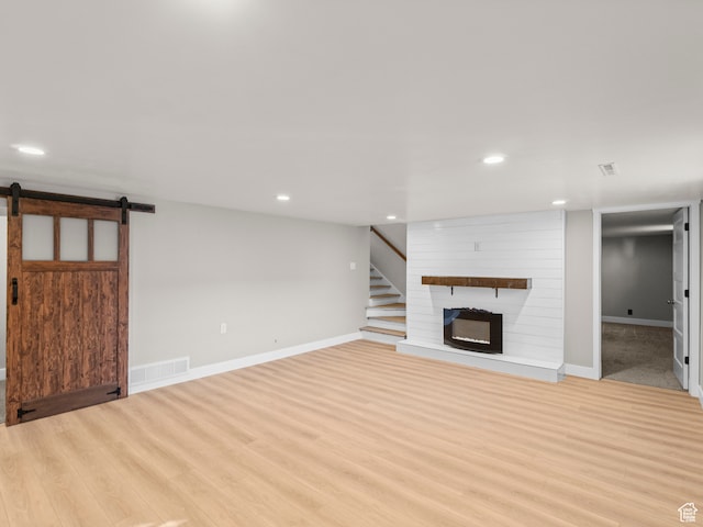 552 E 250 N, Bountiful, UT 84010 - unfurnished living room featuring a large fireplace, a barn door, and light wood-type flooring