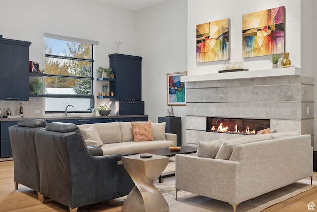 living room with light wood-type flooring, sink, and a tiled fireplace