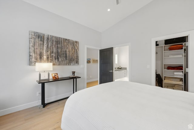 bedroom featuring ensuite bath, a closet, high vaulted ceiling, and light hardwood / wood-style flooring