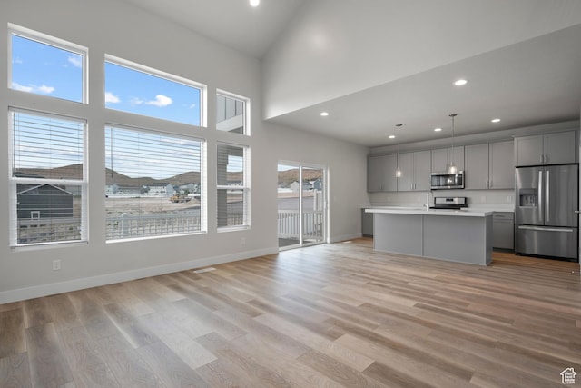 9807 N Aaron Ave Unit 210, Eagle Mountain, UT 84005 - kitchen featuring stainless steel appliances, gray cabinetry, light countertops, open floor plan, and light wood-style flooring
