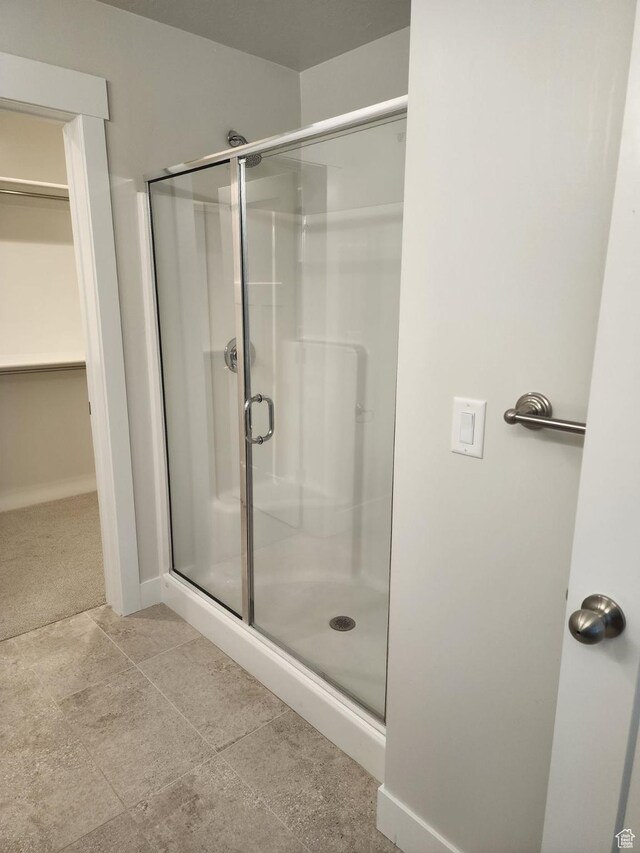 9807 N Aaron Ave Unit 210, Eagle Mountain, UT 84005 - bathroom featuring a stall shower, a walk in closet, and baseboards