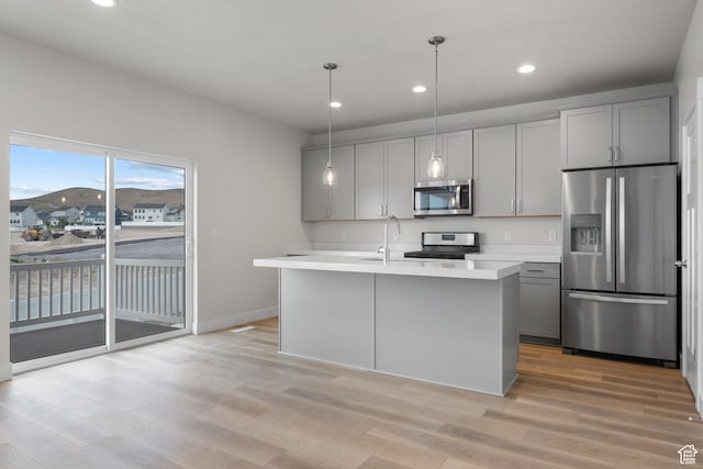 9807 N Aaron Ave Unit 210, Eagle Mountain, UT 84005 - kitchen featuring stainless steel appliances, gray cabinets, light countertops, light wood finished floors, and a center island with sink