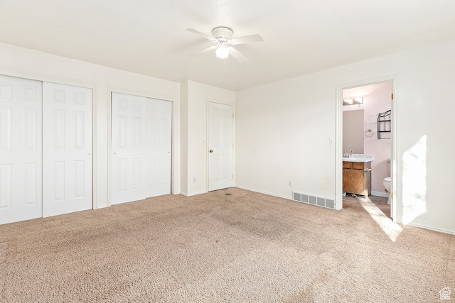 unfurnished bedroom featuring connected bathroom, light colored carpet, and ceiling fan