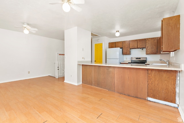 kitchen with electric range, sink, light hardwood / wood-style flooring, kitchen peninsula, and white fridge