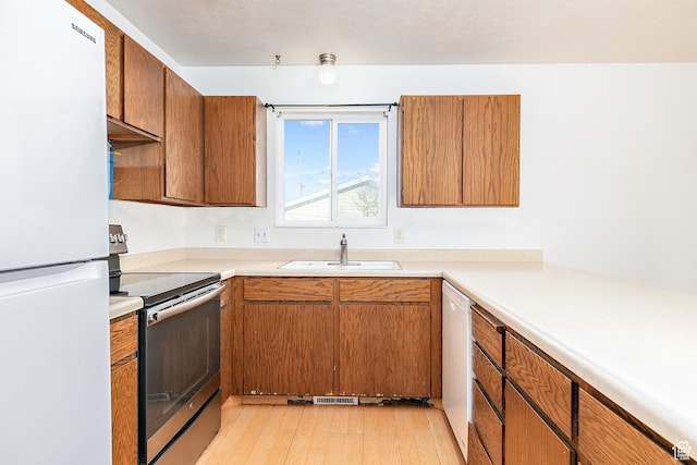 kitchen with white appliances, sink, and light hardwood / wood-style flooring