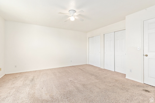 unfurnished bedroom with ceiling fan, carpet, and two closets