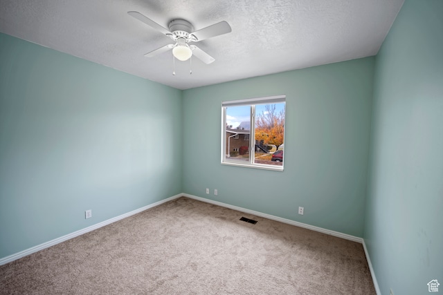 carpeted spare room with a textured ceiling and ceiling fan