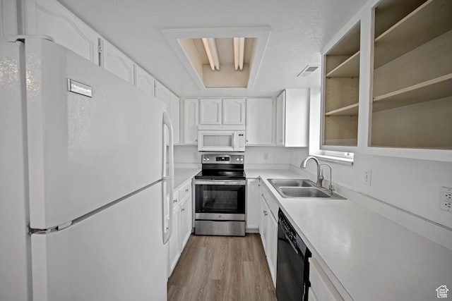 kitchen with light wood-type flooring, a textured ceiling, white appliances, sink, and white cabinetry