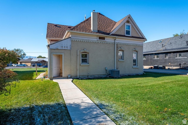 back of house with central air condition unit and a yard