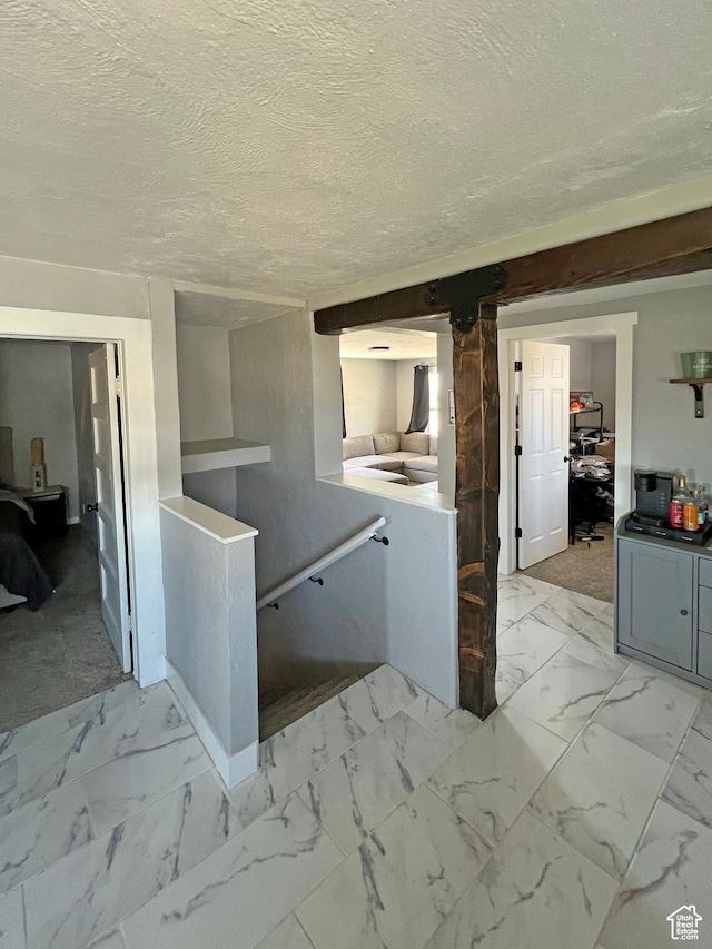 kitchen featuring a textured ceiling, marble finish floor, and gray cabinets