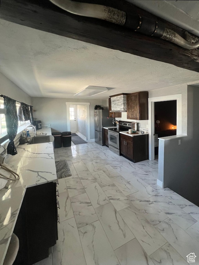 kitchen featuring stainless steel appliances, light countertops, dark brown cabinets, a sink, and baseboards