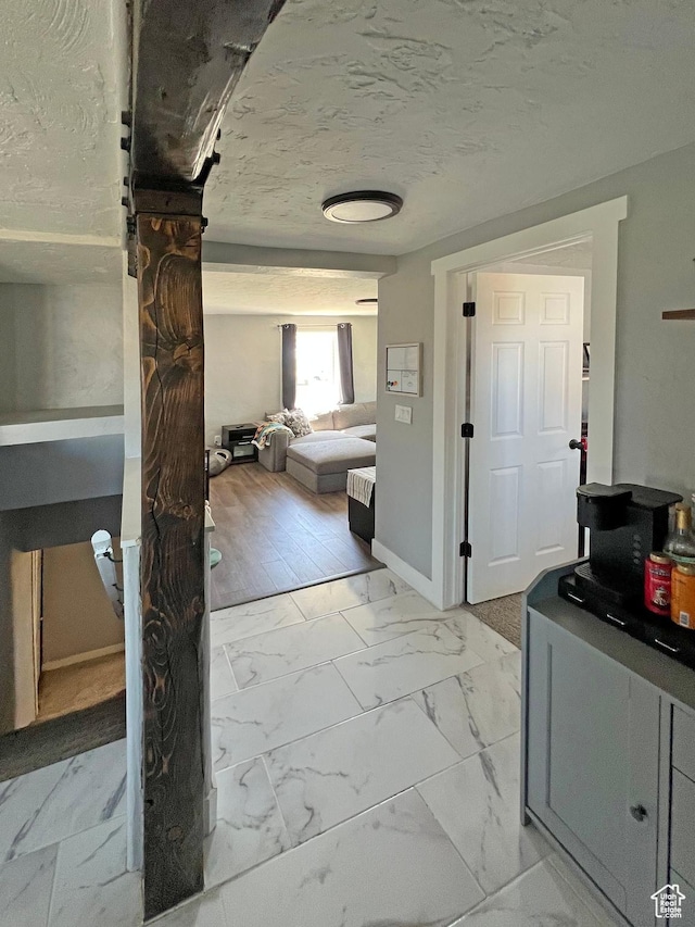 hall featuring a textured ceiling and marble finish floor