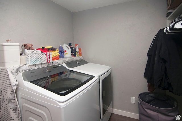 clothes washing area with baseboards, dark wood-style flooring, laundry area, and washing machine and dryer
