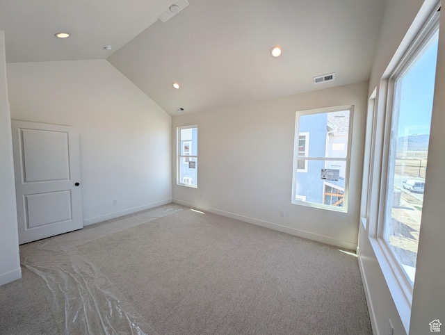 empty room with visible vents, baseboards, carpet floors, and lofted ceiling